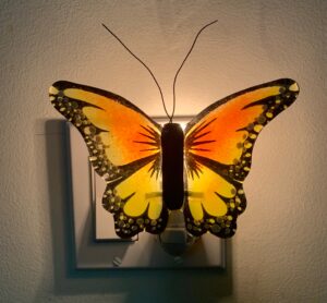 A backlit yellow, orange and black fused glass butterfly nightlight.