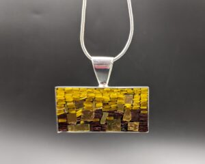 A micromosaic pendant with brown, ochre and gold filati. Filati is a tiny stick of glass that is cut down into smaller sections.