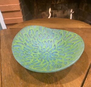 This is a aqua blue and light green fused glass bowl with a design showing the transparency of the colors in the glass.
