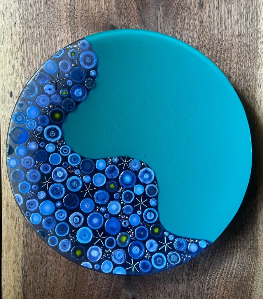 Top view of the award dish. Blue and green fused glass with 3 D raised elements on the wavy blue section.