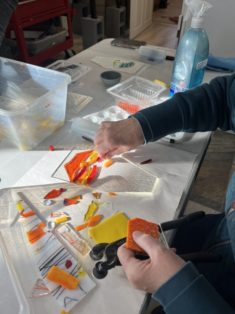 Workshop attendee arranges cut glass on her fused glass base.